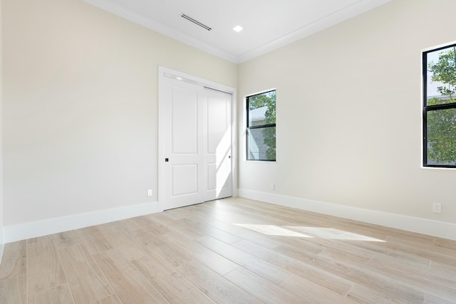 unfurnished room with crown molding, a healthy amount of sunlight, and light hardwood / wood-style flooring