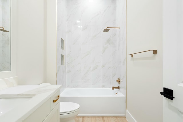 full bathroom with tiled shower / bath, hardwood / wood-style flooring, vanity, and toilet