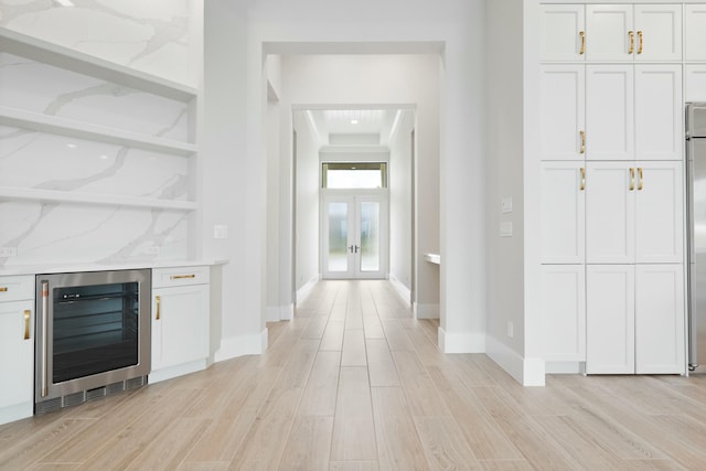 corridor with french doors, wine cooler, and light hardwood / wood-style flooring