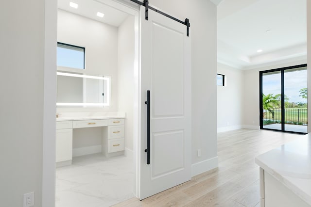 corridor featuring a barn door and a tray ceiling