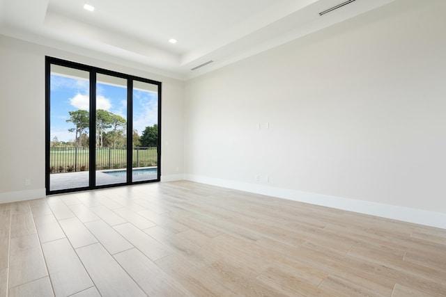 spare room featuring light hardwood / wood-style flooring and a raised ceiling