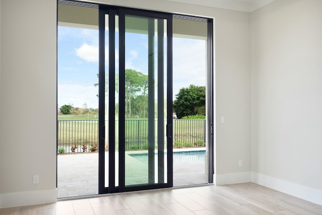 doorway to outside featuring a water view and light hardwood / wood-style flooring