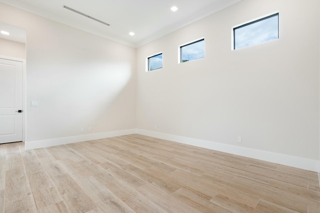 empty room with ornamental molding, light hardwood / wood-style flooring, and a wealth of natural light