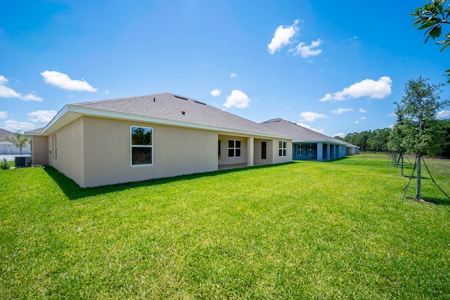 rear view of house with central AC and a yard