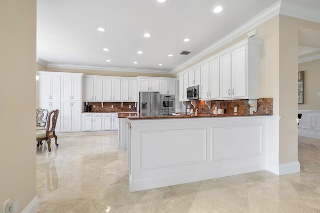 kitchen featuring kitchen peninsula, ornamental molding, appliances with stainless steel finishes, white cabinets, and backsplash