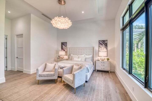 bedroom featuring light hardwood / wood-style flooring, a towering ceiling, and a notable chandelier