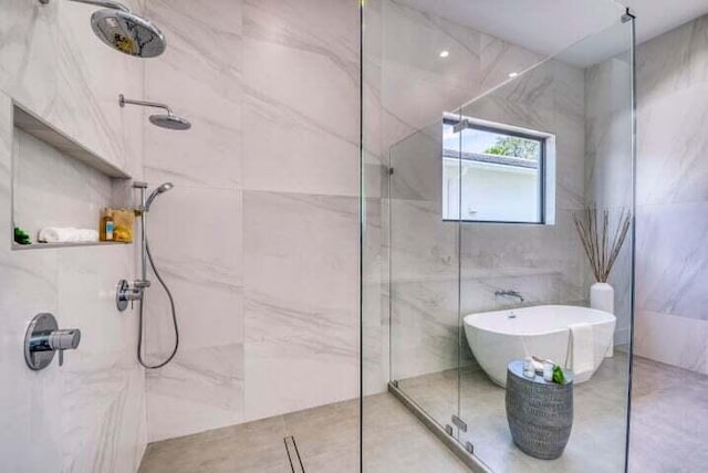 bathroom with shower with separate bathtub, tile patterned flooring, and tile walls