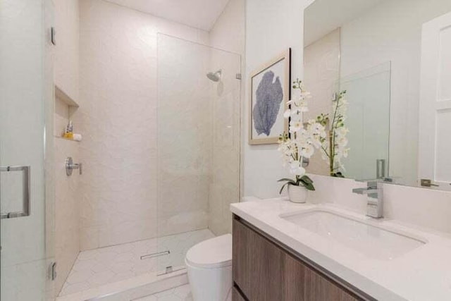 bathroom featuring a shower with shower door, vanity, and toilet