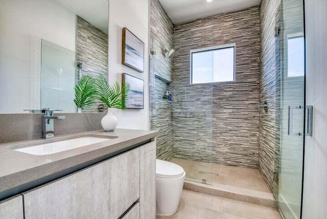 bathroom featuring vanity, toilet, tile patterned floors, and a shower with shower door