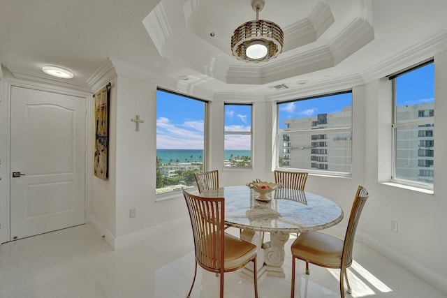 dining room featuring a water view, crown molding, a tray ceiling, and light tile patterned floors