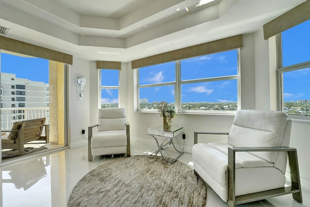 living area with a raised ceiling and light tile patterned flooring