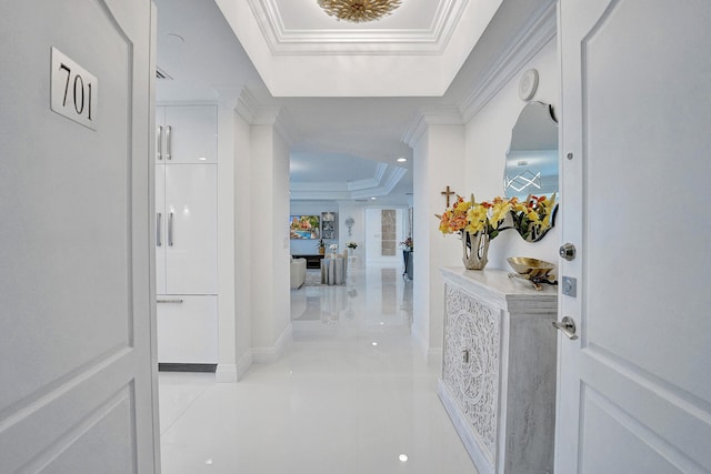 hall featuring ornamental molding, light tile patterned flooring, and a raised ceiling