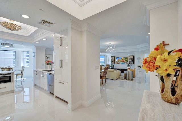 hall with sink, crown molding, and a tray ceiling