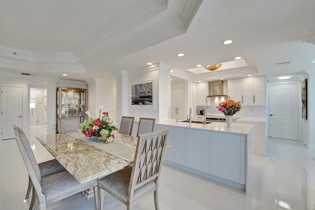 dining space featuring light tile patterned flooring, ornamental molding, sink, and a raised ceiling