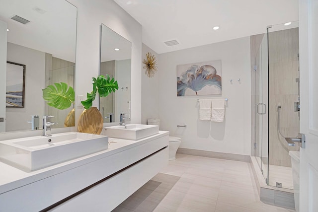 bathroom featuring tile patterned floors, vanity, toilet, and a shower with shower door