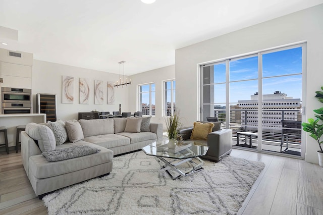 living room featuring beverage cooler, light hardwood / wood-style flooring, and a chandelier