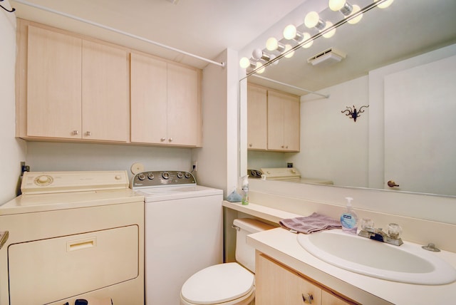 bathroom featuring toilet, vanity, and washer and clothes dryer