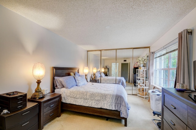 bedroom with light carpet, a closet, and a textured ceiling