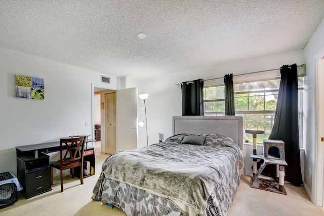 bedroom featuring light carpet and a textured ceiling