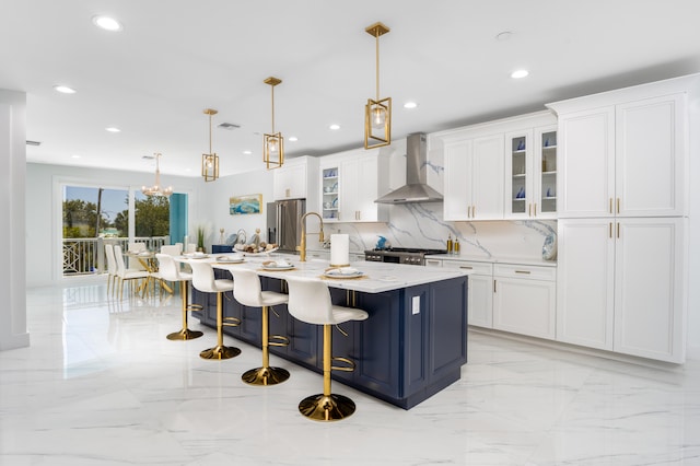 kitchen featuring white cabinets, a center island with sink, stainless steel fridge, decorative light fixtures, and wall chimney exhaust hood