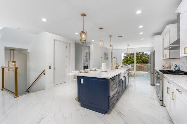 kitchen with stainless steel appliances, light tile patterned floors, a kitchen island with sink, white cabinetry, and blue cabinets