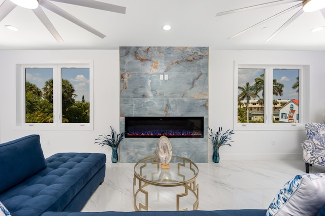 tiled living room featuring a high end fireplace, ceiling fan, and a healthy amount of sunlight