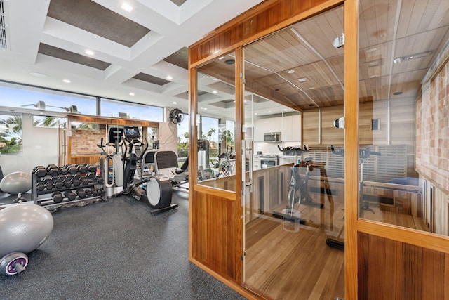 exercise room featuring coffered ceiling and hardwood / wood-style flooring