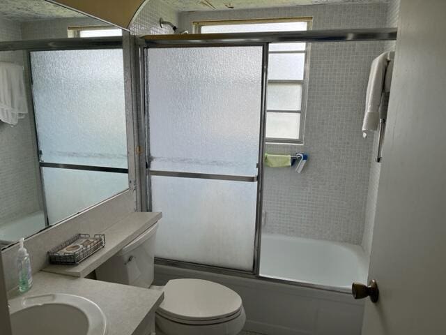 full bathroom featuring toilet, vanity, and bath / shower combo with glass door