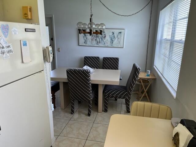 dining space featuring light tile floors and an inviting chandelier