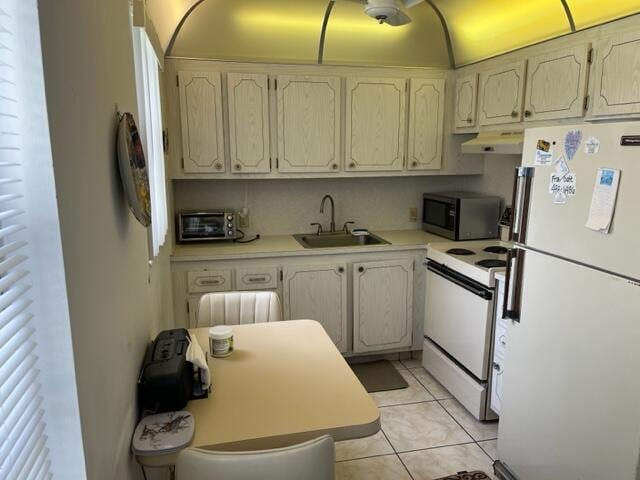 kitchen with white appliances, sink, and light tile floors