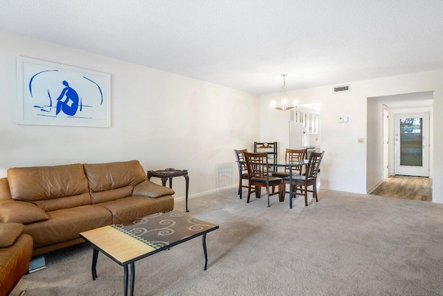 living room featuring an inviting chandelier, light carpet, and a textured ceiling