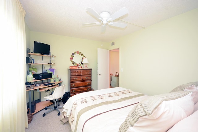 carpeted bedroom with ceiling fan and a textured ceiling