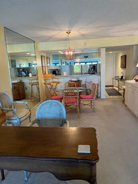 carpeted dining area with a textured ceiling and a notable chandelier