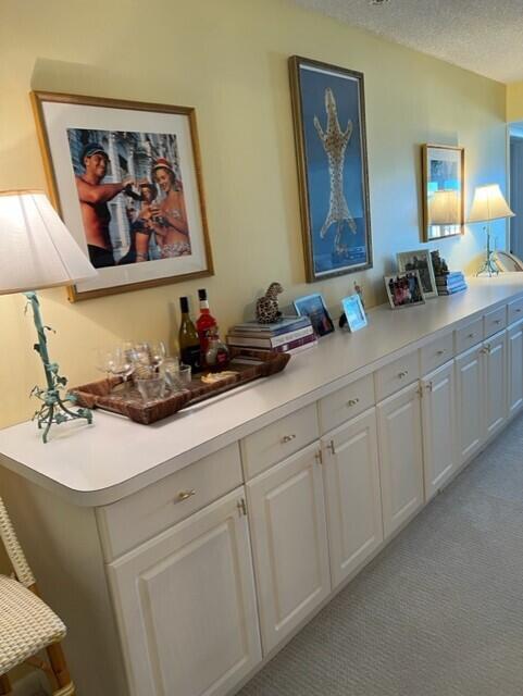 interior space with a textured ceiling, light colored carpet, and white cabinetry