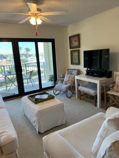 living room with ceiling fan, carpet floors, and a textured ceiling