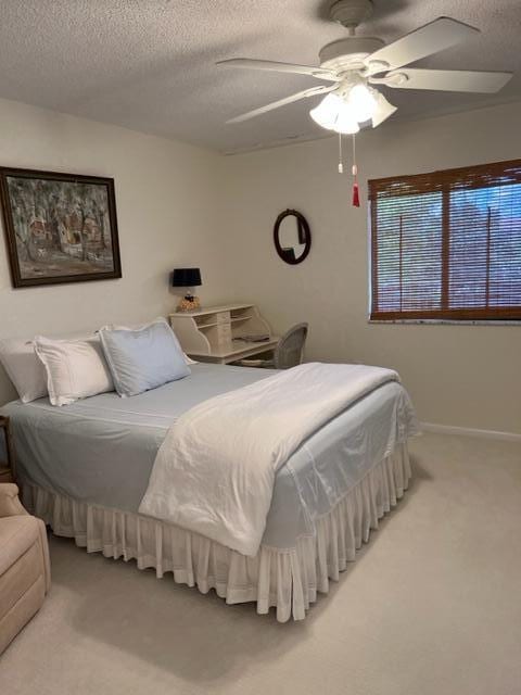 bedroom featuring ceiling fan, carpet floors, and a textured ceiling