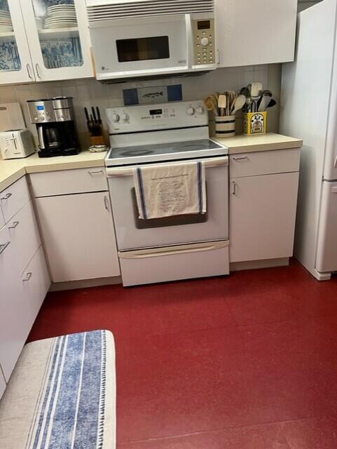 kitchen with white cabinetry and white appliances