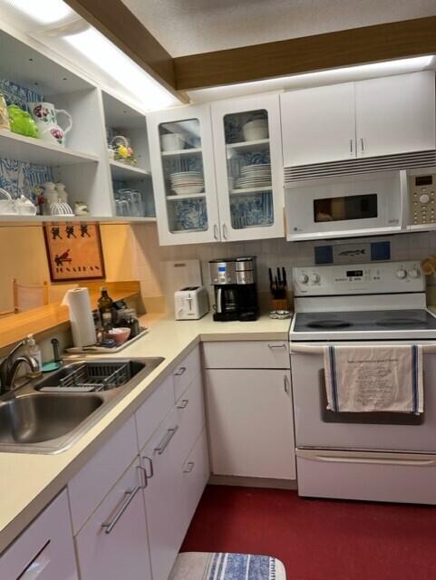 kitchen with sink, white cabinets, and white appliances