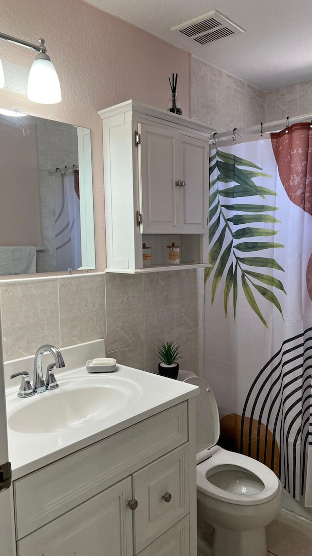 bathroom with backsplash, toilet, vanity, and tile walls