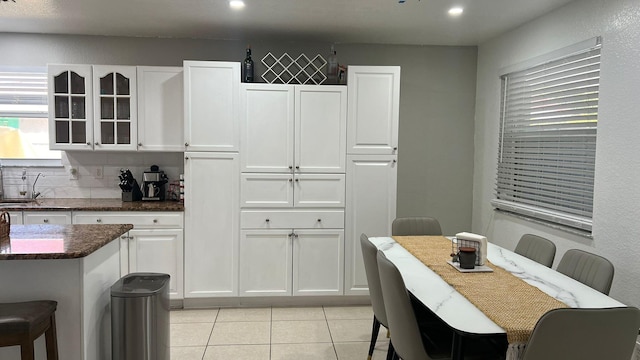 kitchen featuring sink, a breakfast bar, white cabinetry, and light tile flooring