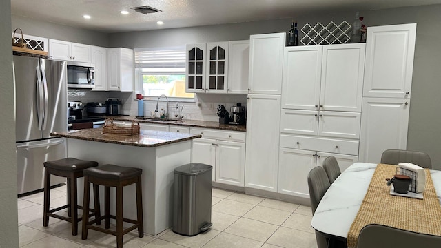 kitchen featuring backsplash, stainless steel appliances, a kitchen island, and white cabinetry