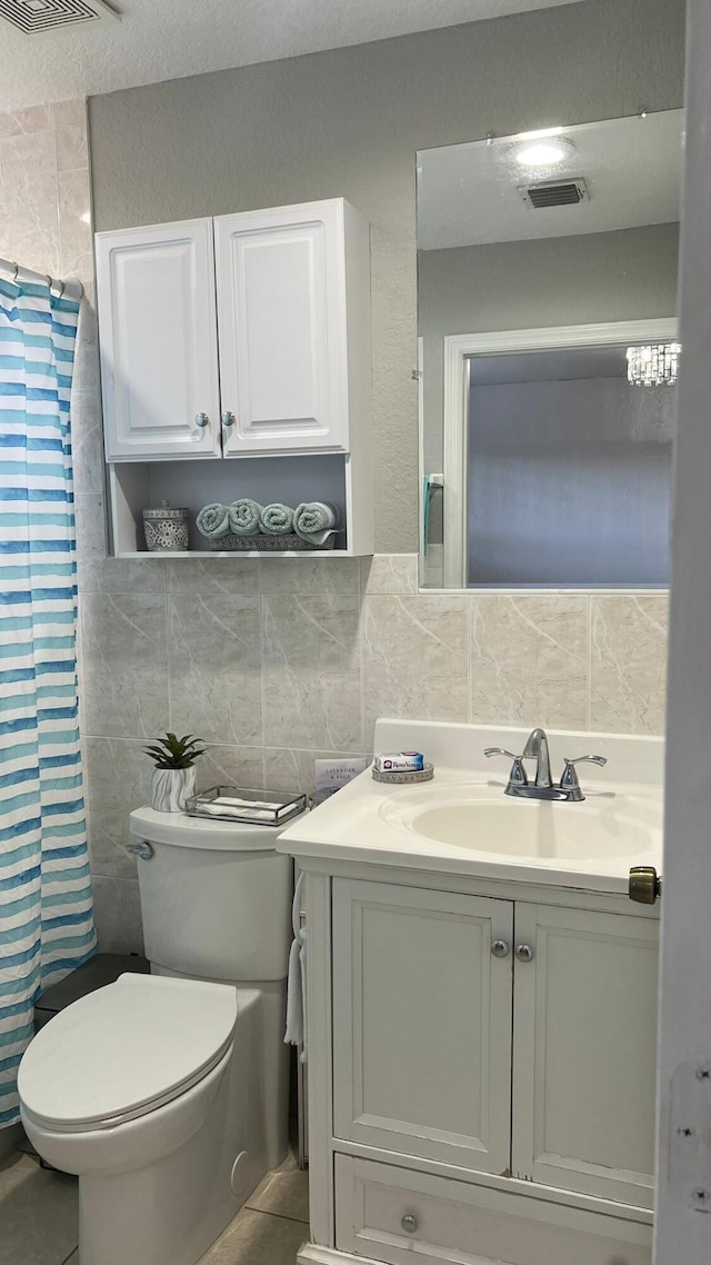 bathroom with tile walls, tile floors, toilet, and vanity