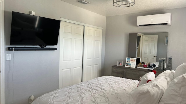 bedroom featuring a wall mounted AC, a closet, and a textured ceiling