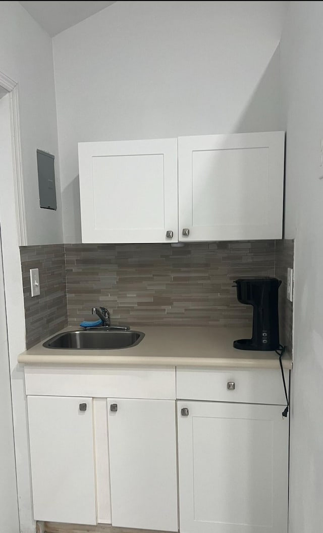 kitchen featuring tasteful backsplash, white cabinetry, and sink