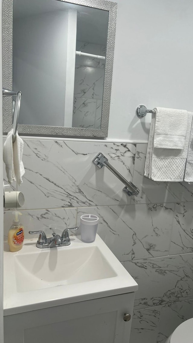 bathroom featuring vanity, toilet, and tile walls