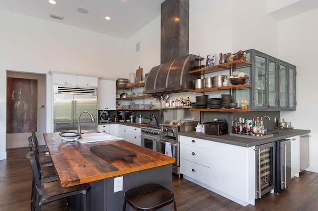 kitchen with a kitchen bar, high end appliances, white cabinets, dark hardwood / wood-style floors, and sink