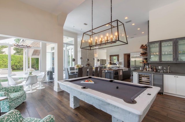 game room with wine cooler, dark hardwood / wood-style flooring, pool table, and a towering ceiling