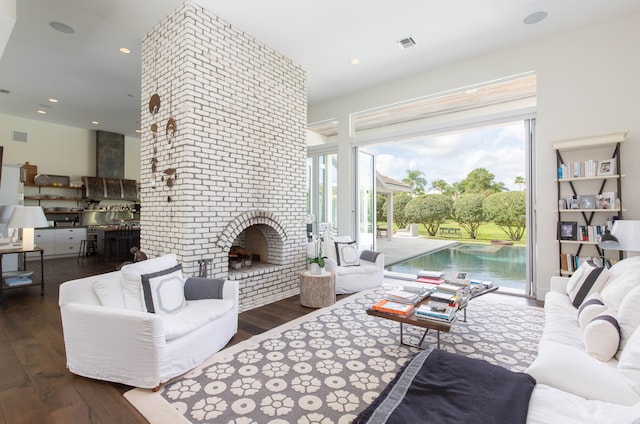 living room featuring plenty of natural light, brick wall, dark wood-type flooring, and a brick fireplace