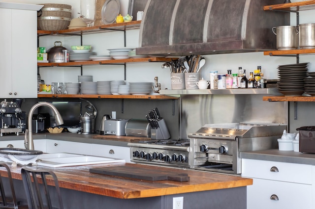 kitchen featuring white cabinets, sink, and wooden counters