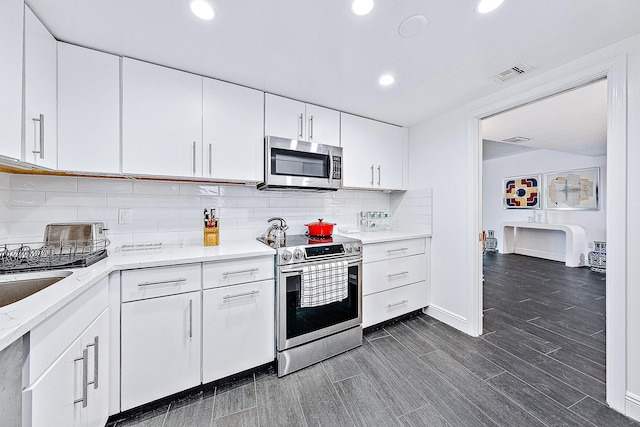 kitchen featuring white cabinetry, backsplash, dark wood-type flooring, and stainless steel appliances